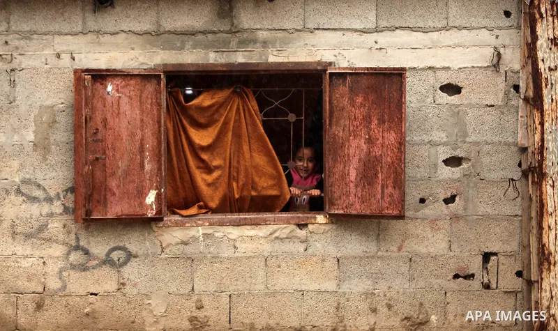 A Palestinian girl looks through a window during the cold and rainy weather in the Jabalia refugee camp in the northern Gaza Strip on January 28, 2017. Photo by Ashraf Amra