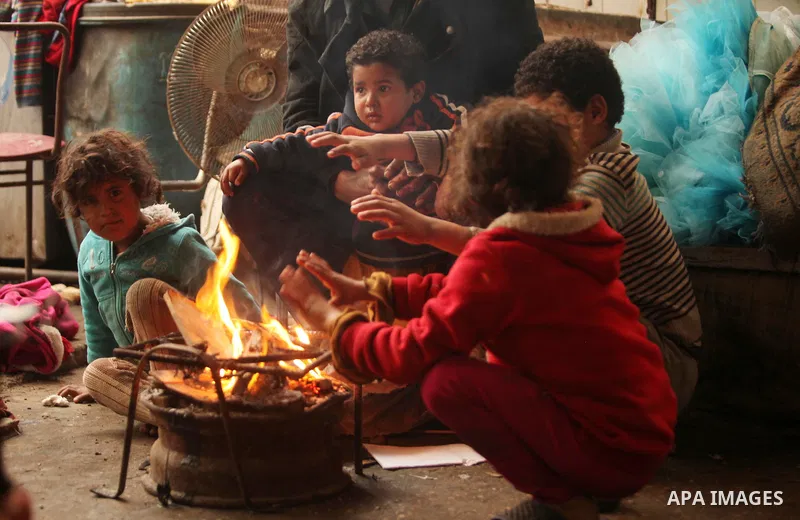 Palestinian children warm up in front of a fire in a hovel during the cold and rainy weather in the Jabalia refugee camp in the northern Gaza Strip on January 28, 2017. Photo by Ashraf Amra