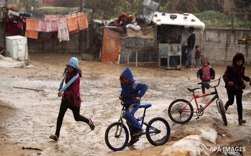 Palestinian girls run on a wet street during the cold and rainy weather in the Jabalia refugee camp in the northern Gaza Strip on January 28, 2017. Photo by Ashraf Amra