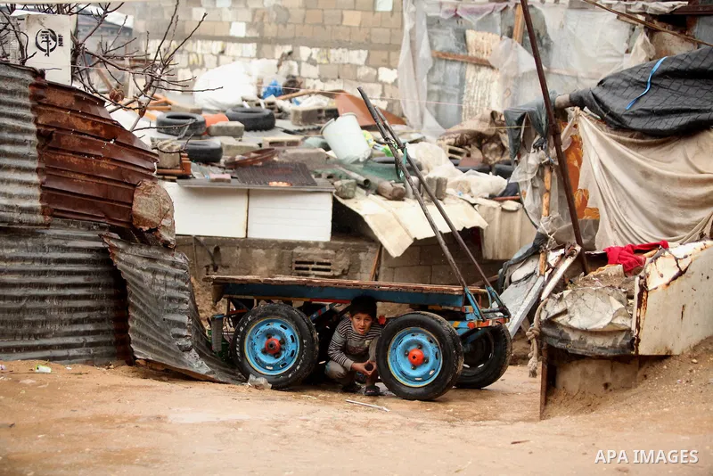 A Palestinian boy sits under a cart during the cold and rainy weather in the Jabalia refugee camp in the northern Gaza Strip on January 28, 2017. Photo by Ashraf Amra