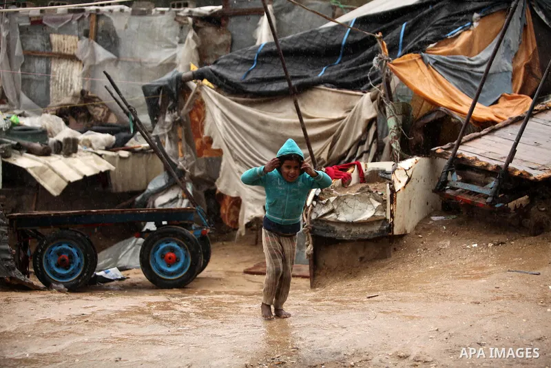 A Palestinian girl plays outside a hovel during the cold and rainy weather in the Jabalia refugee camp in the northern Gaza Strip on January 28, 2017. Photo by Ashraf Amra