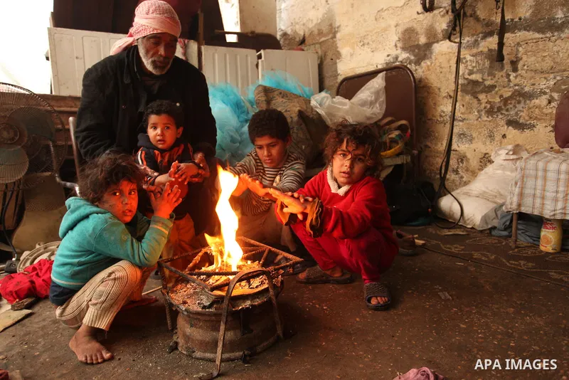 Palestinian children warm up in front of a fire in a hovel during the cold and rainy weather in the Jabalia refugee camp in the northern Gaza Strip on January 28, 2017. Photo by Ashraf Amra