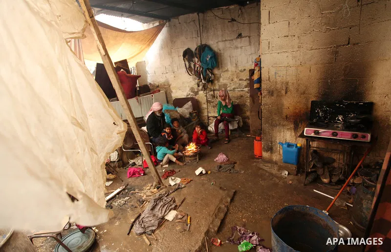 Palestinian children warm up in front of a fire in a hovel during the cold and rainy weather in the Jabalia refugee camp in the northern Gaza Strip on January 28, 2017. Photo by Ashraf Amra