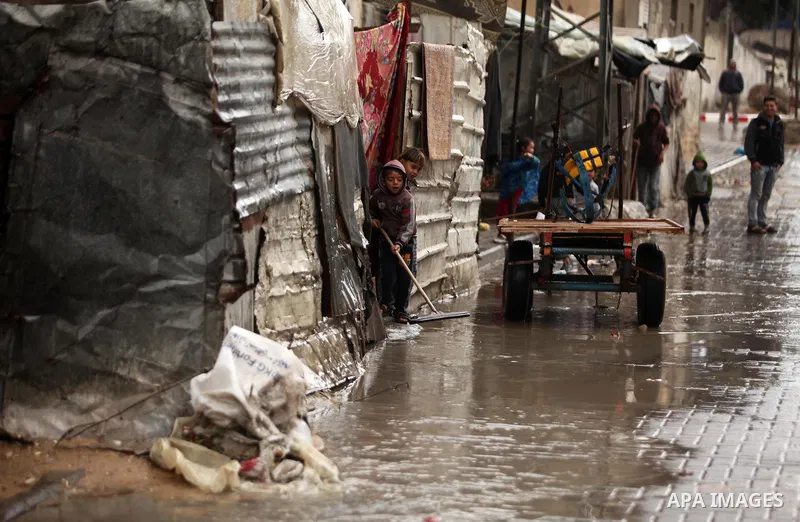Palestinian boys mop up the water from a wet street during the cold and rainy weather in the town of Beit Lahia in the northern Gaza Strip on January 28, 2017. Photo by Ashraf Amra