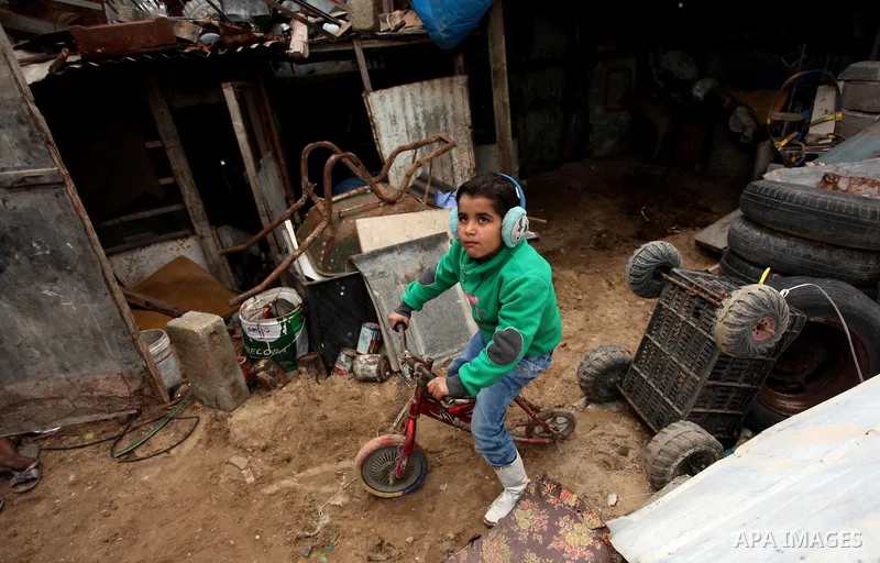 A Palestinian boy plays outside a hovel during the cold weather in the Jabalia refugee camp in the northern Gaza Strip on January 29, 2017. Photo by Ashraf Amra