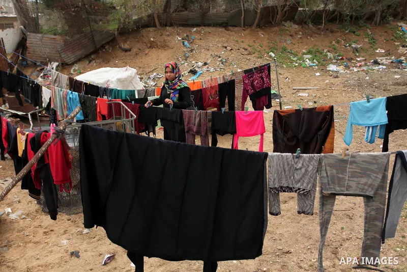 A Palestinian woman hangs laundry on a rope to dry outside her hovel during the cold weather in the Jabalia refugee camp in the northern Gaza Strip on January 29, 2017. Photo by Ashraf Amra