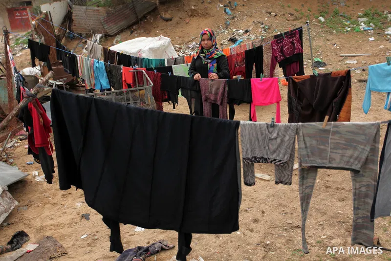 A Palestinian woman hangs laundry on a rope to dry outside her hovel during the cold weather in the Jabalia refugee camp in the northern Gaza Strip on January 29, 2017. Photo by Ashraf Amra
