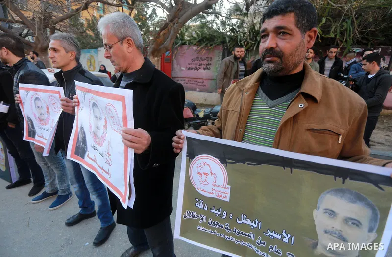 Palestinians hold placards during a protest to show solidarity with Palestinian prisoners held in Israeli Jails, in front of Red cross office in Gaza city, on January 30, 2017. Photo by Mohammed Asad
