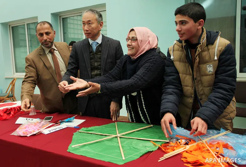 Japanese Ambassador to Palestine, Takeshi Okubo, helps Palestinian students to prepare kites at the headquarters United Nations Relief and Works Agency (UNRWA), in Gaza city, on Feb. 01, 2017. Photo by Ashraf Amra