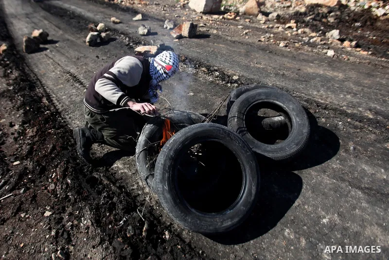 A Palestinian protester burns tires during clashes with Israeli security forces following a demonstration against the expropriation of Palestinian land by Israel in the village of Kfar Qaddum, near Nablus, in the occupie...