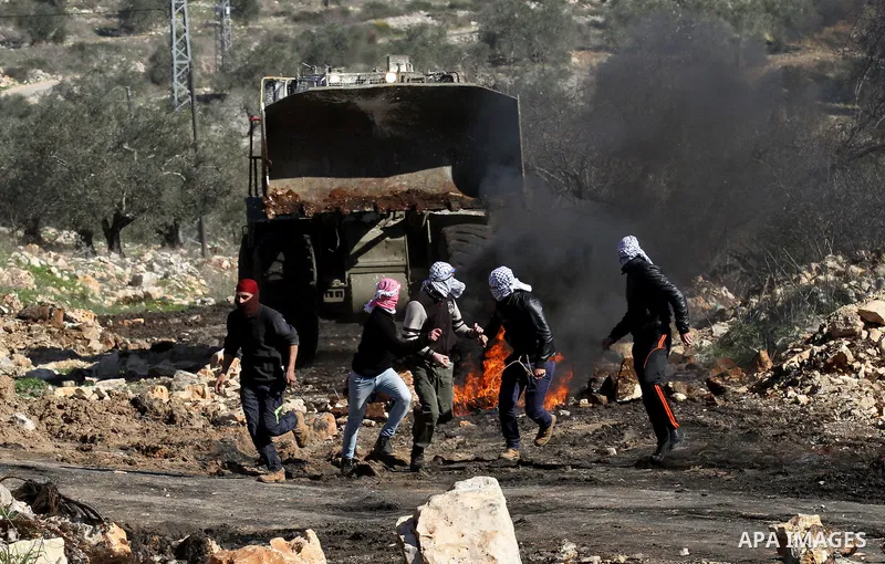 Palestinian protesters run during clashes with Israeli security forces following a demonstration against the expropriation of Palestinian land by Israel in the village of Kfar Qaddum, near Nablus, in the occupied West Ba...