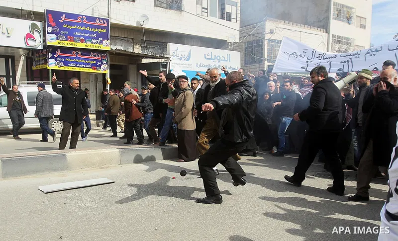Palestinian protesters run for cover during clashes with Palestinian policemen following a demonstration against a decision by the Palestinian Authority to grant a public land to the Russian church, in the West Bank city...