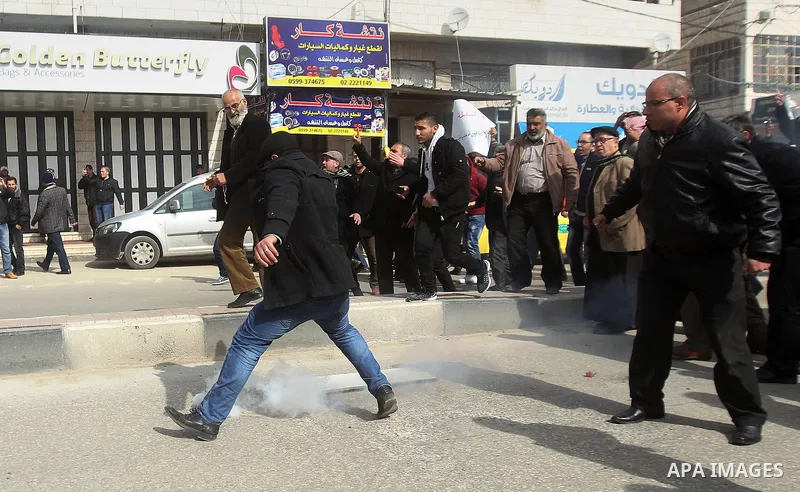 Palestinian protesters run for cover during clashes with Palestinian policemen following a demonstration against a decision by the Palestinian Authority to grant a public land to the Russian church, in the West Bank city...