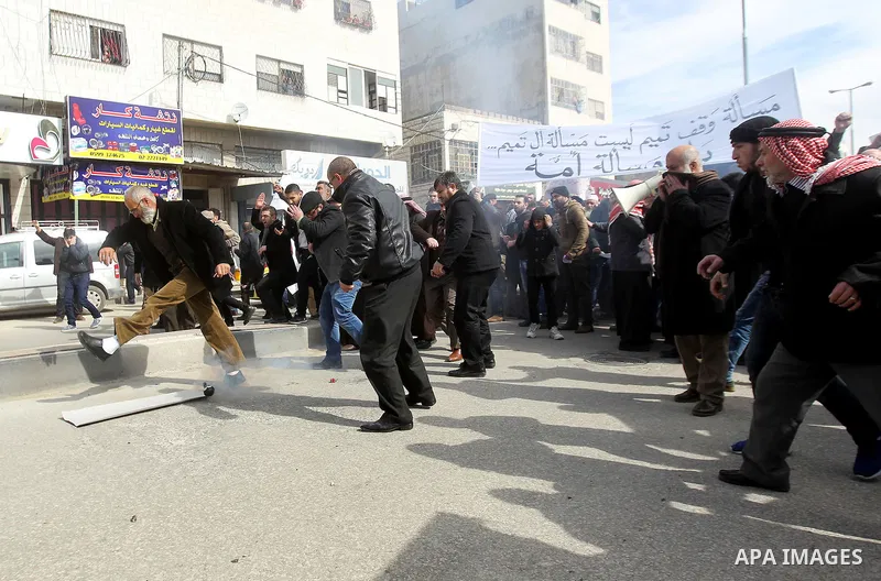 Palestinian protesters run for cover during clashes with Palestinian policemen following a demonstration against a decision by the Palestinian Authority to grant a public land to the Russian church, in the West Bank city...