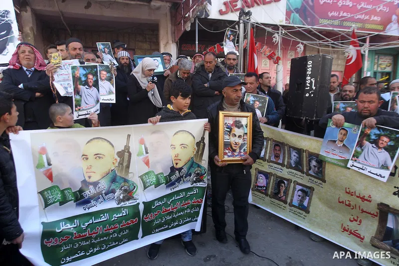 Palestinians hold posters bearing a portrait of Palestinian journalist Mohammed al-Qiq who is imprisoned in an Israeli jail during a protest in the West Bank city of Hebron, on February 10, 2017. Photo by Wisam Hashlamou...