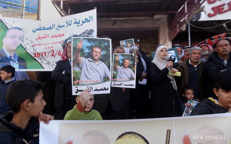 Palestinians hold posters bearing a portrait of Palestinian journalist Mohammed al-Qiq who is imprisoned in an Israeli jail during a protest in the West Bank city of Hebron, on February 10, 2017. Photo by Wisam Hashlamou...