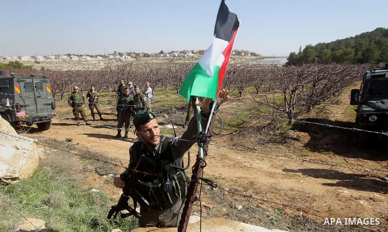 An Israeli border policeman removes the Palestine flag during a demonstration against the construction of Jewish settlements in the occupied West Bank city of Hebron, on February 10, 2017. Photo by Wisam Hashlamoun