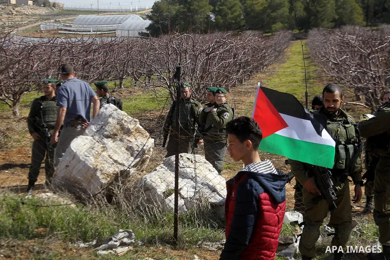 Palestinian protesters holds a national flag during a demonstration against the construction of Jewish settlements in the occupied West Bank city of Hebron, on February 10, 2017. Photo by Wisam Hashlamoun