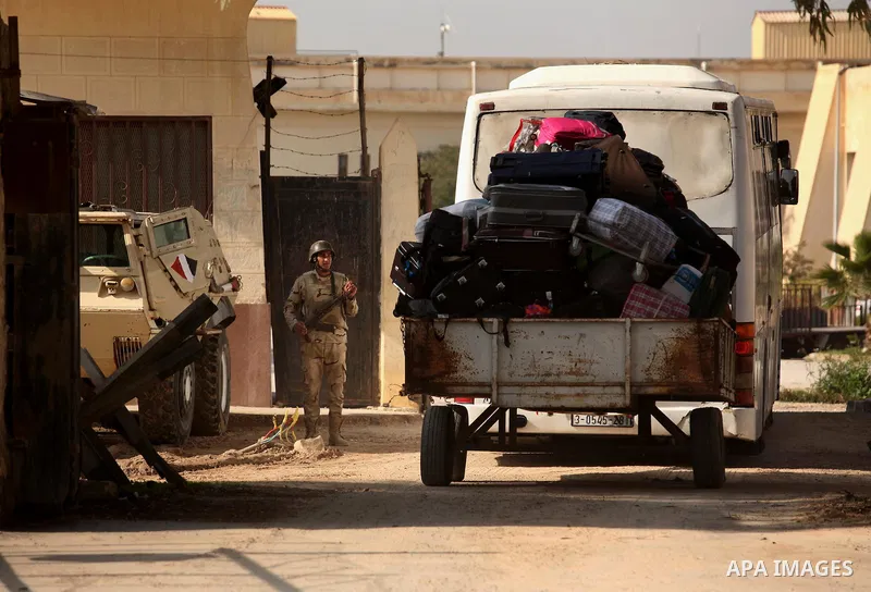 An Egyptian soldier stands guard as Palestinians wait for travel permits to cross into Egypt through the Rafah border crossing after it was opened by Egyptian authorities for humanitarian cases, in Rafah in the southern...