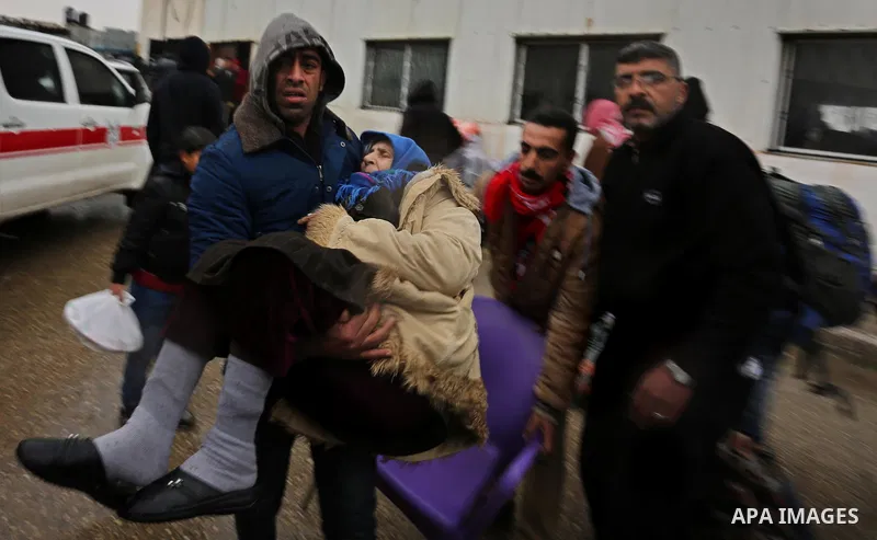 A Palestinian man carries an elderly woman into a bus as she waits to cross into Egypt through the Rafah border crossing, after it was opened by Egyptian authorities for humanitarian cases, on a rainy day, in Rafah in th...