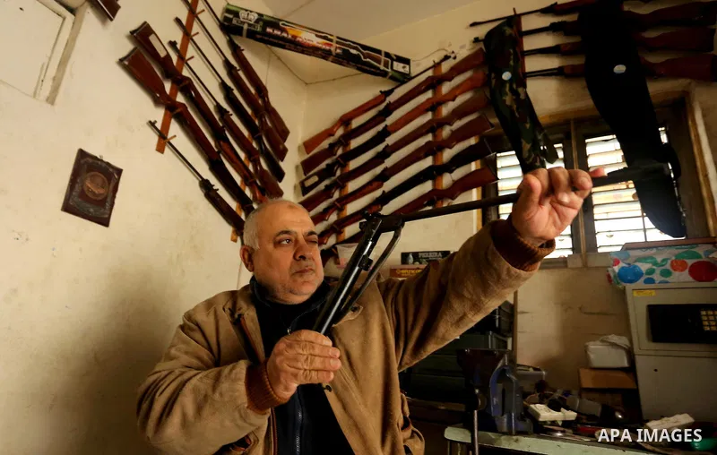 Khalil Taima, a 53-year-old Palestinian man, fixes the barrel of an air rifle used for target-shooting and hunting at his shop in the Nuseirat refugee camp in the central Gaza Strip on February 13, 2017. Photo by Ashraf...