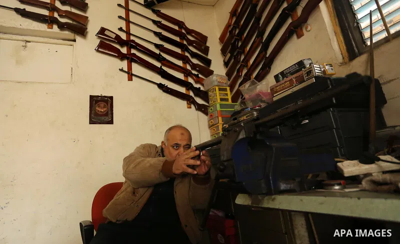 Khalil Taima, a 53-year-old Palestinian man, fixes the barrel of an air rifle used for target-shooting and hunting at his shop in the Nuseirat refugee camp in the central Gaza Strip on February 13, 2017. Photo by Ashraf...