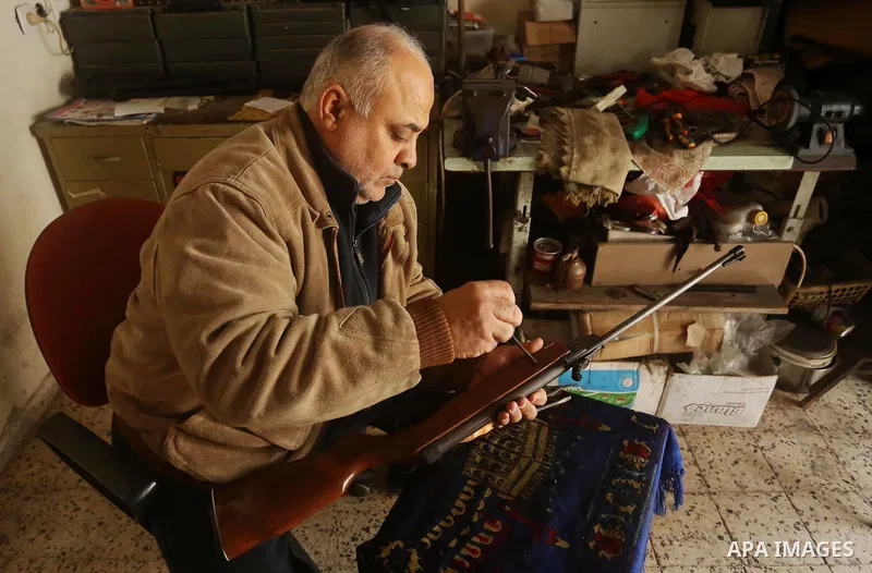 Khalil Taima, a 53-year-old Palestinian man, fixes the barrel of an air rifle used for target-shooting and hunting at his shop in the Nuseirat refugee camp in the central Gaza Strip on February 13, 2017. Photo by Ashraf...