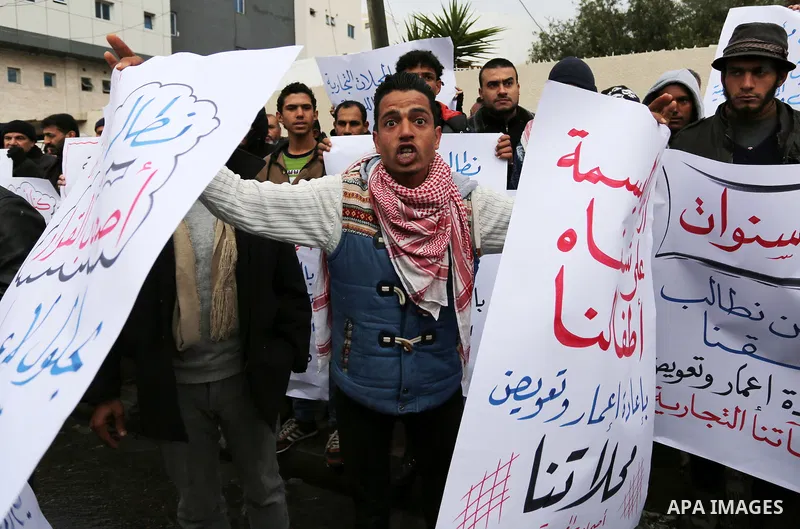 Palestinian owners of factories hold banners during a protest demanding to reconstruction their factories which was destroyed during the 50-day war between Israel and Hamas militants in the summer of 2014, in Gaza city o...