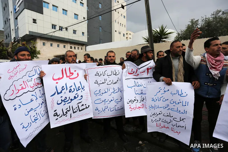 Palestinian owners of factories hold banners during a protest demanding to reconstruction their factories which was destroyed during the 50-day war between Israel and Hamas militants in the summer of 2014, in Gaza city o...