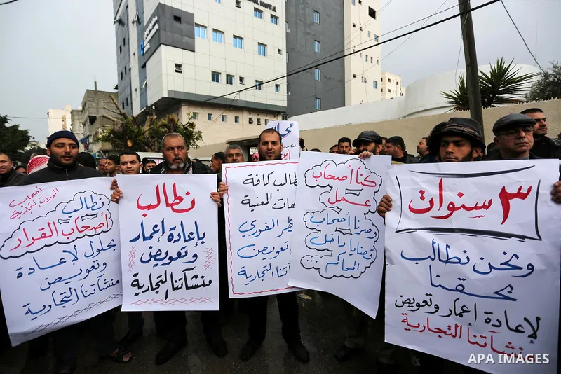 Palestinian owners of factories hold banners during a protest demanding to reconstruction their factories which was destroyed during the 50-day war between Israel and Hamas militants in the summer of 2014, in Gaza city o...