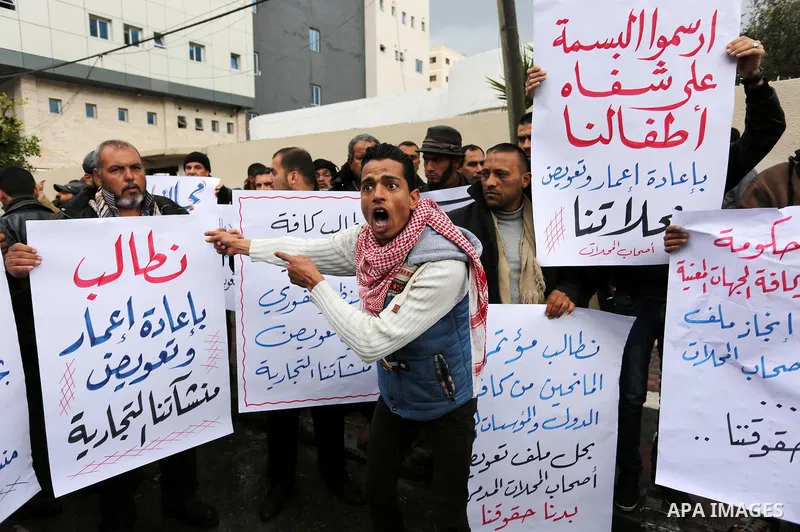 Palestinian owners of factories hold banners during a protest demanding to reconstruction their factories which was destroyed during the 50-day war between Israel and Hamas militants in the summer of 2014, in Gaza city o...