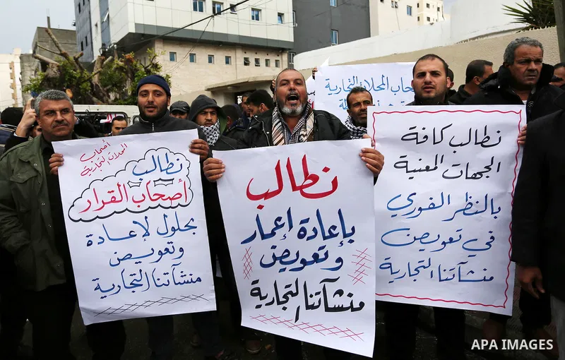 Palestinian owners of factories hold banners during a protest demanding to reconstruction their factories which was destroyed during the 50-day war between Israel and Hamas militants in the summer of 2014, in Gaza city o...