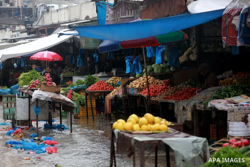 Palestinians walk through a wet street during a rainy day at a market at the Al-Shati refugee camp in Gaza City on February 14, 2017. Photo by Mohammed Asad