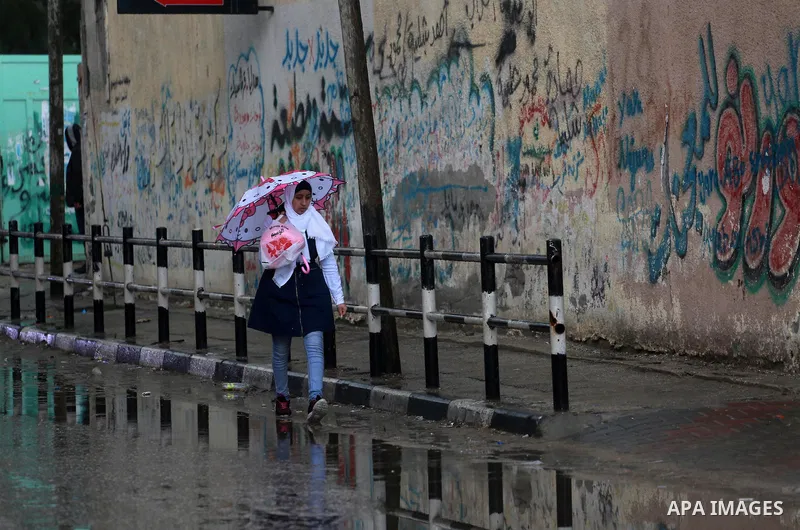 A female Palestinian student walks through a wet street during a rainy day in Gaza City on February 14, 2017. Photo by Mohammed Asad