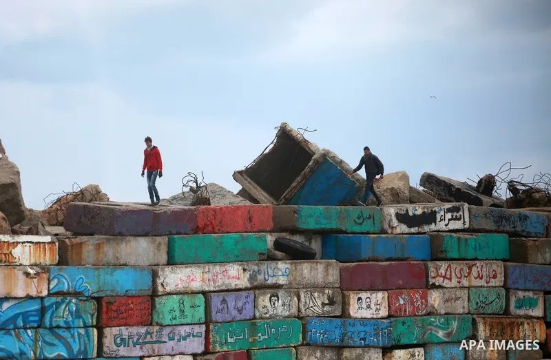 Palestinians stand on wall at the Gaza seaport during a rainy day in Gaza City on February 14, 2017. Photo by Mohammed Asad