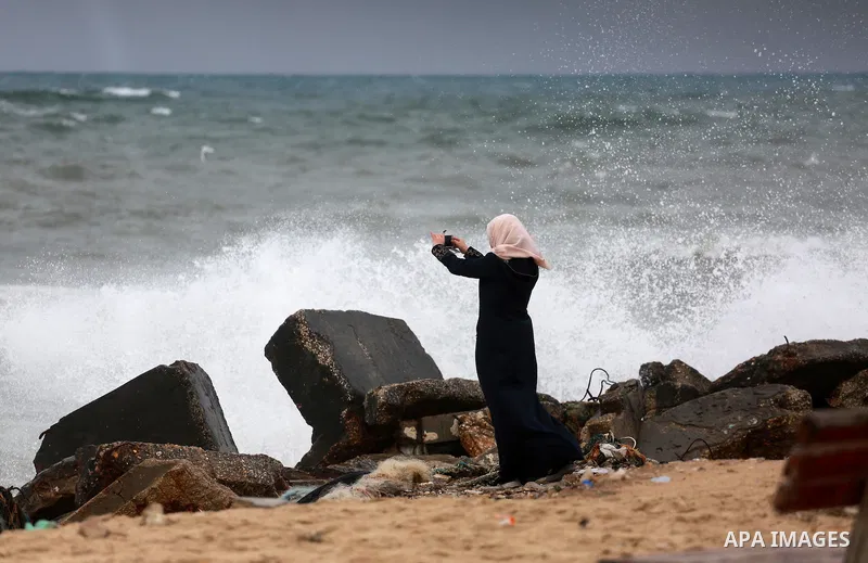 A Palestinian woman takes a photo at the Gaza seaport during a rainy day in Gaza City on February 14, 2017. Photo by Mohammed Asad