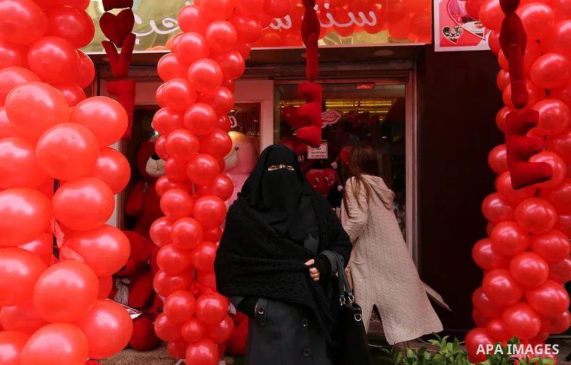 Palestinians walk past a shop selling red teddy bears, red ballons and pillows on Valentine's day in Gaza city on February 14, 2017. Valentine's Day is increasingly popular in the region as people have taken up the custo...