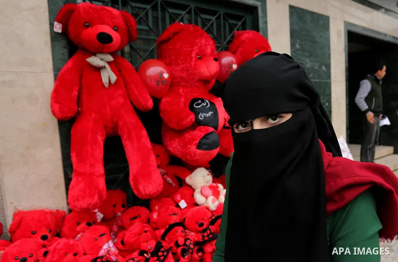 A Palestinian woman poses for a photo with red teddy bears outside a shop on Valentine's day in Gaza city on February 14, 2017. Valentine's Day is increasingly popular in the region as people have taken up the custom of...