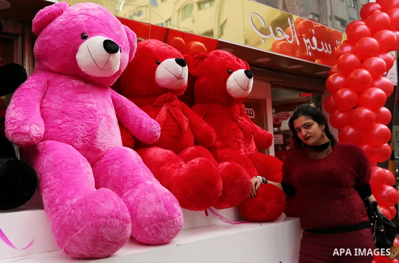 A Palestinian woman poses for a photo with red teddy bears outside a shop on Valentine's day in Gaza city on February 14, 2017. Valentine's Day is increasingly popular in the region as people have taken up the custom of...