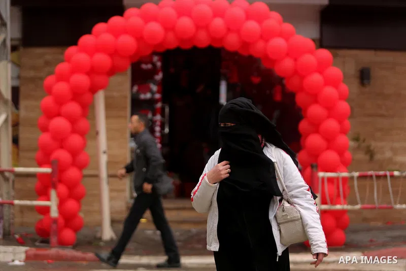 Palestinians walk past a shop selling red teddy bears, red ballons and pillows on Valentine's day in Gaza city on February 14, 2017. Valentine's Day is increasingly popular in the region as people have taken up the custo...