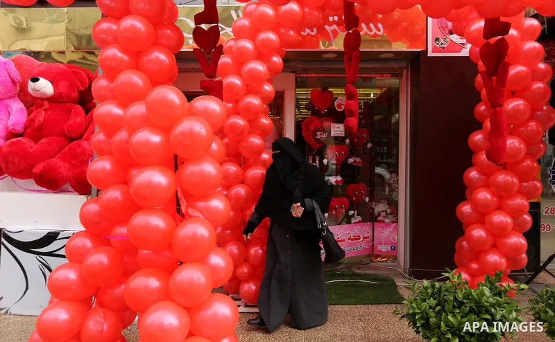 Palestinians walk past a shop selling red teddy bears, red ballons and pillows on Valentine's day in Gaza city on February 14, 2017. Valentine's Day is increasingly popular in the region as people have taken up the custo...