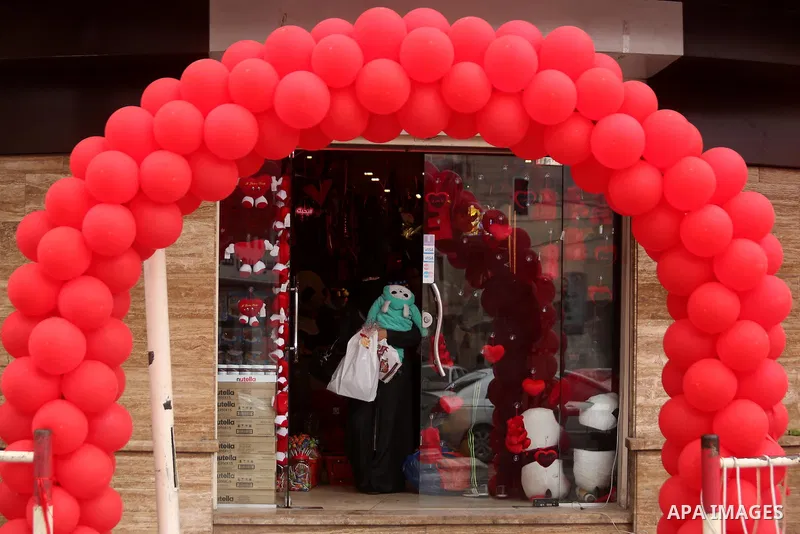 Palestinians walk past a shop selling red teddy bears, red ballons and pillows on Valentine's day in Gaza city on February 14, 2017. Valentine's Day is increasingly popular in the region as people have taken up the custo...