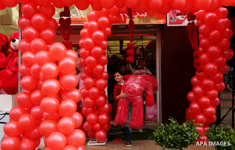 Palestinians walk past a shop selling red teddy bears, red ballons and pillows on Valentine's day in Gaza city on February 14, 2017. Valentine's Day is increasingly popular in the region as people have taken up the custo...