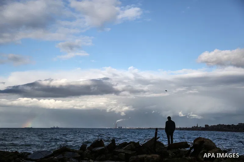 A Palestinian man stands on a rock at the Gaza seaport during a rainy and cold weather at Al-Shati refugee camp in Gaza City on February 15, 2017. Photo by Mohammed Dahman