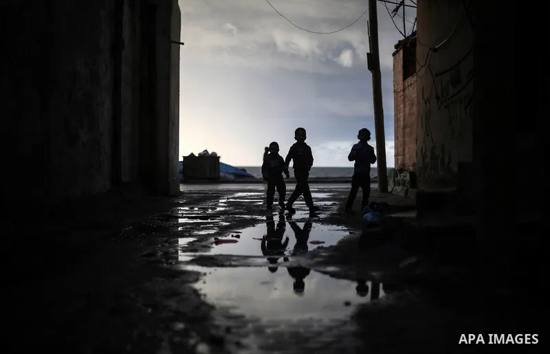 Palestinian children play at the wet street during a rainy and cold weather at Al-Shati refugee camp in Gaza City on February 15, 2017. Photo by Mohammed Dahman