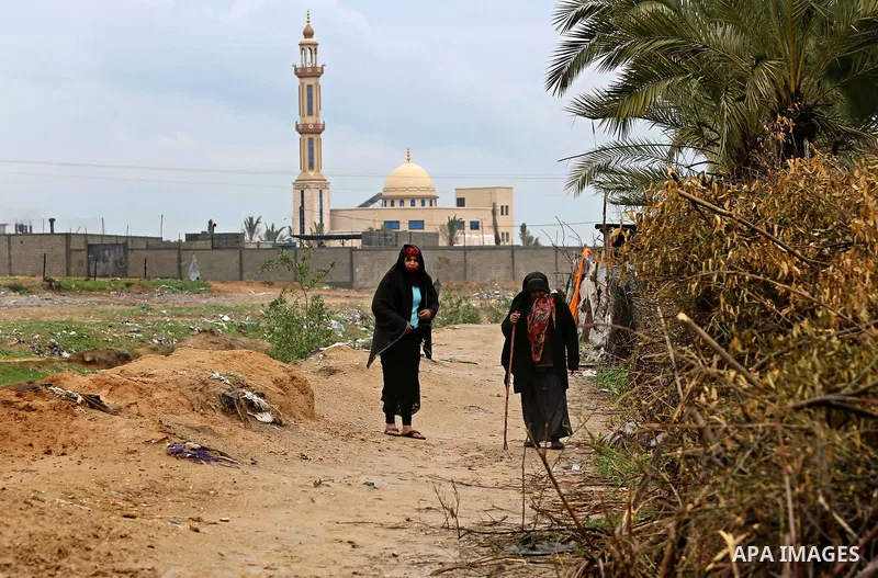 Palestinian Bedouin women walk during a heavy rainfall, in the al-Moghraqa in the center Gaza Strip, on February 16, 2017. Photo by Ashraf Amra