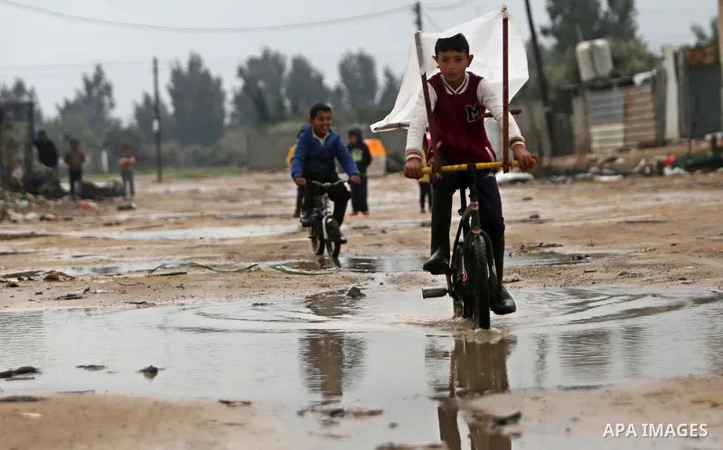 Palestinian boys ride bicycle in a flooded area following heavy rainfall in the al-Moghraqa in the center Gaza Strip, on February 16, 2017. Photo by Ashraf Amra