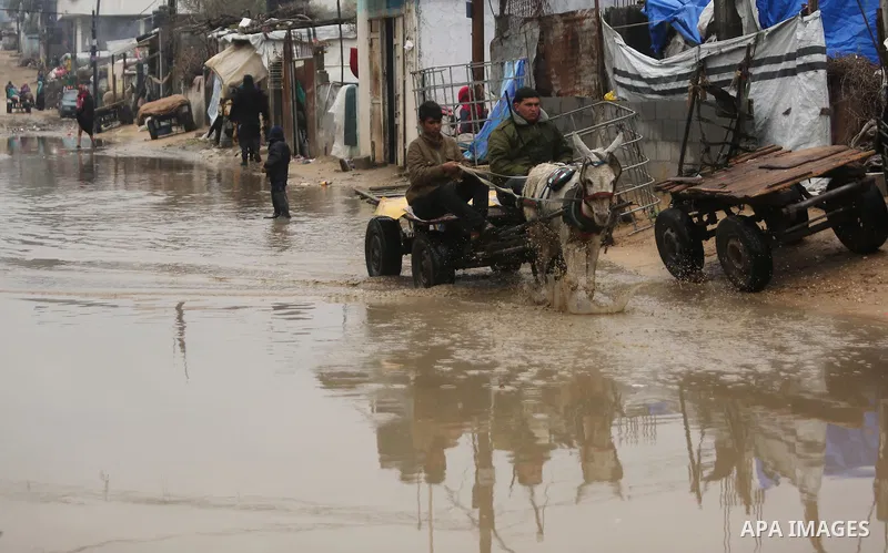 Palestinian men ride a donkey cart in a flooded area following heavy rainfall in the al-Moghraqa in the center Gaza Strip, on February 16, 2017. Photo by Ashraf Amra