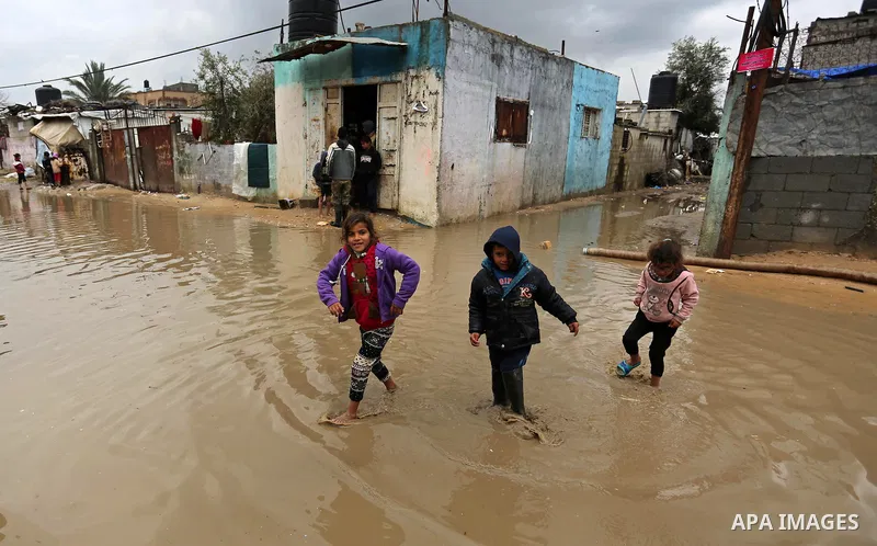 Palestinian children walk in a flooded area following heavy rainfall in Gaza city,on February 16, 2017. Photo by Ashraf Amra