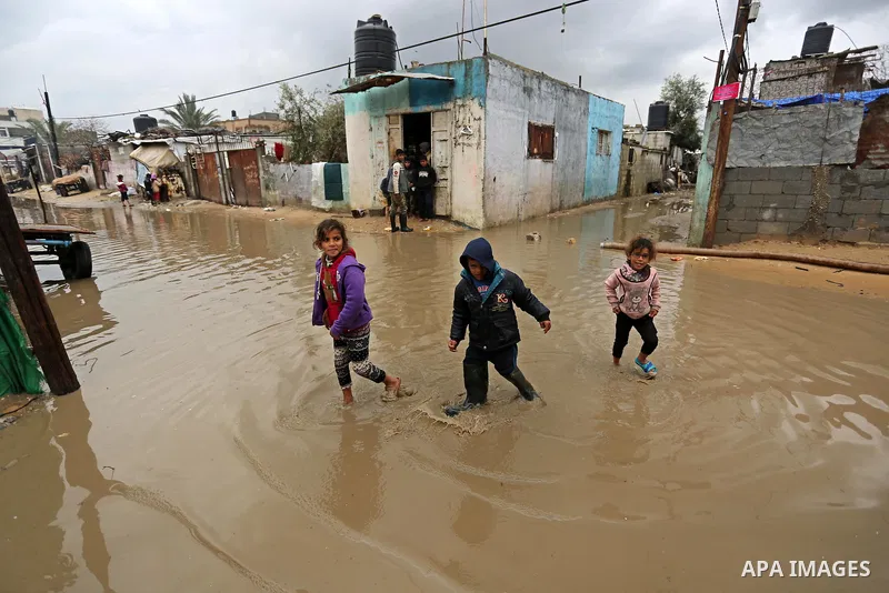 Palestinian children walk in a flooded area following heavy rainfall in Gaza city,on February 16, 2017. Photo by Ashraf Amra